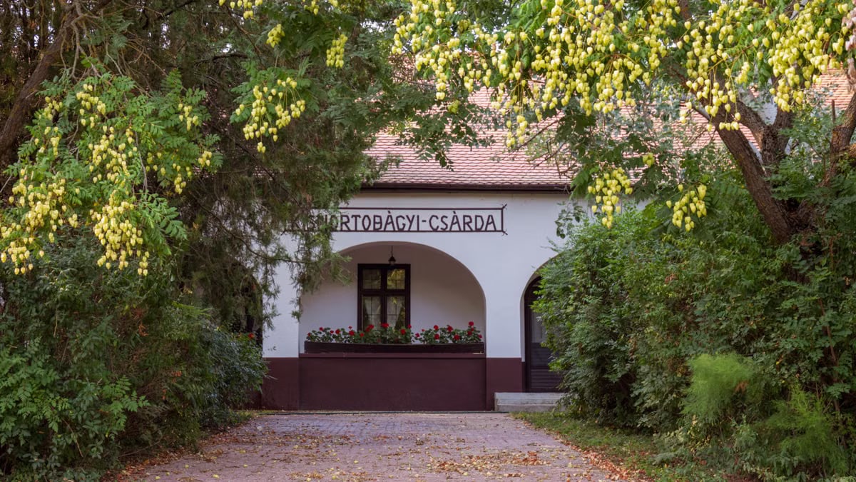 Charming country inn surrounded by rich foliage and vibrant flowers in a serene setting.
